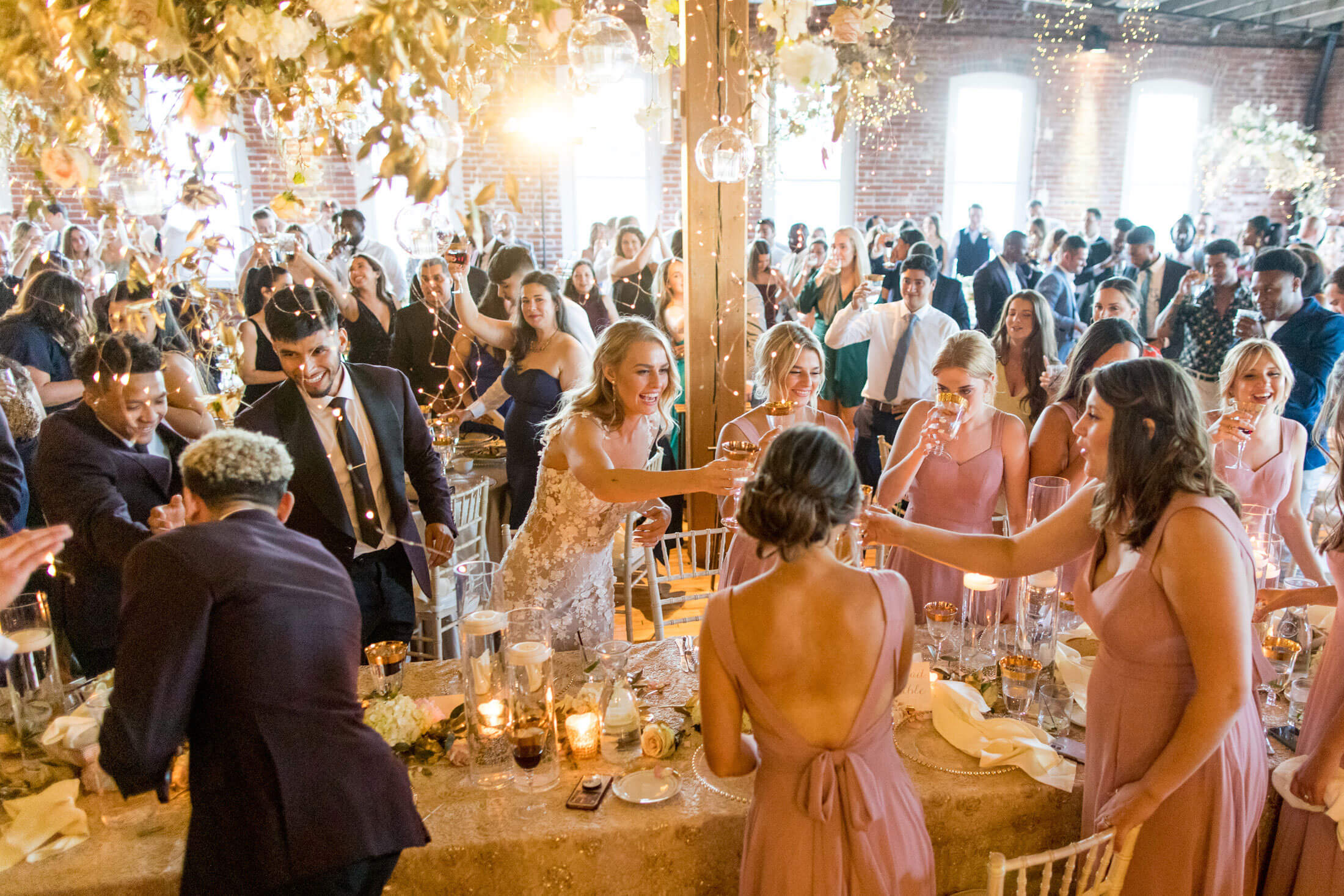 Wedding reception table giving a toast, gold details with twinkling lights from ceiling